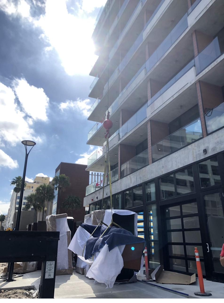 Crane lifting furniture to upper hotel floor — coordinated logistics in action