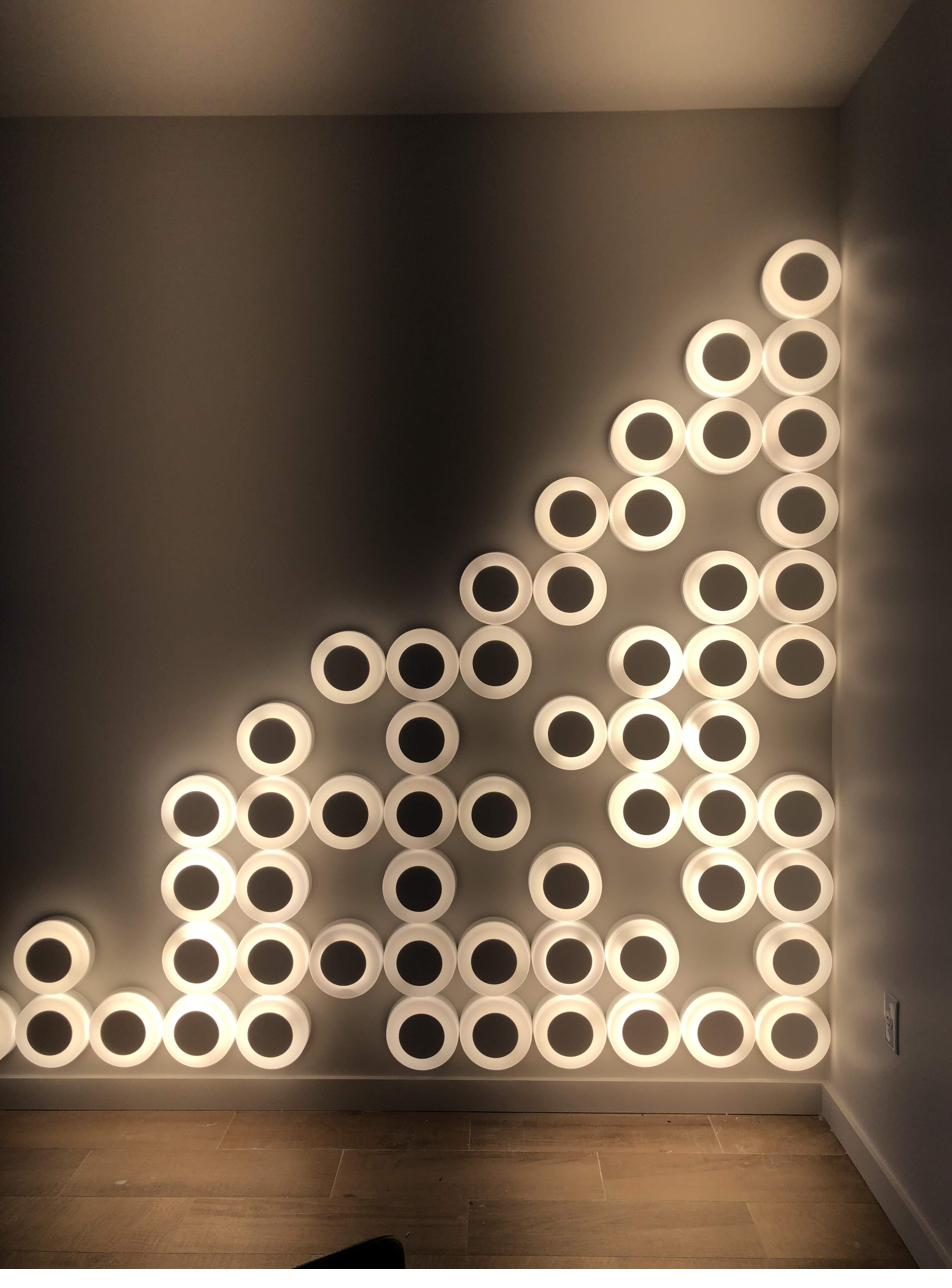 Geometric arrangement of illuminated wall rings creating an architectural lighting installation