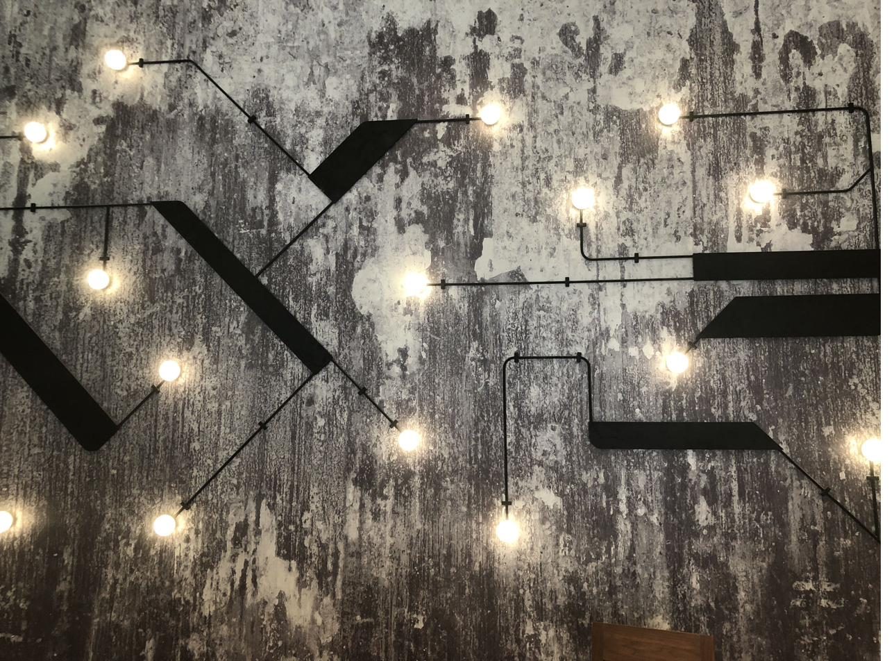 Industrial geometric exposed-conduit lighting installation on raw concrete wall