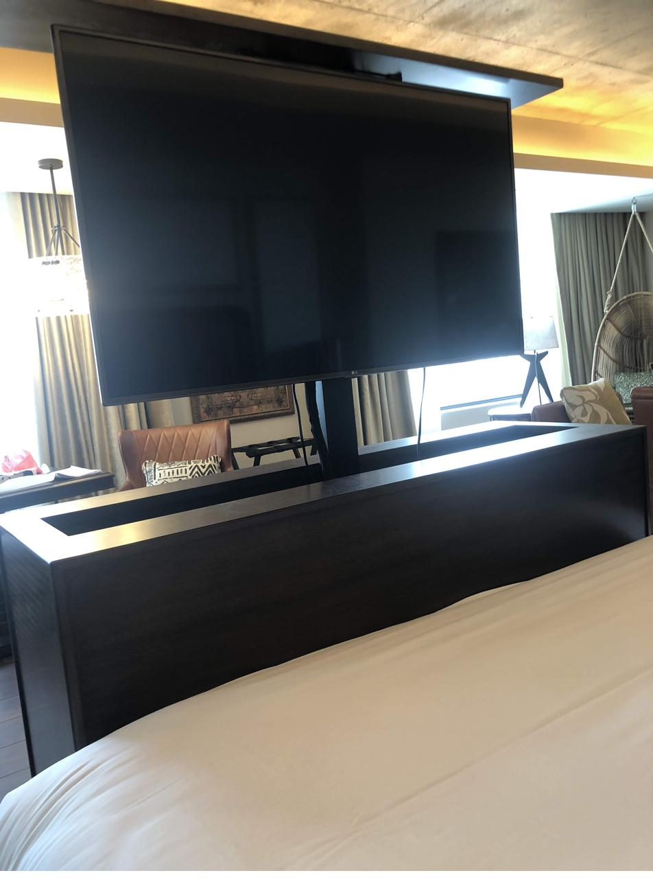 Pop-up TV mounted in custom footboard cabinet — specialty AV install