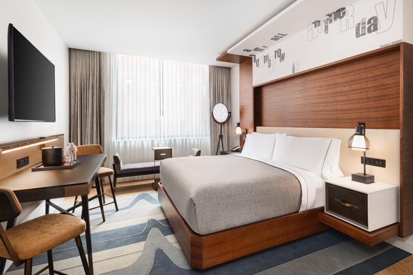 Hotel guest room with installed bedding, drapery, and upholstered pieces